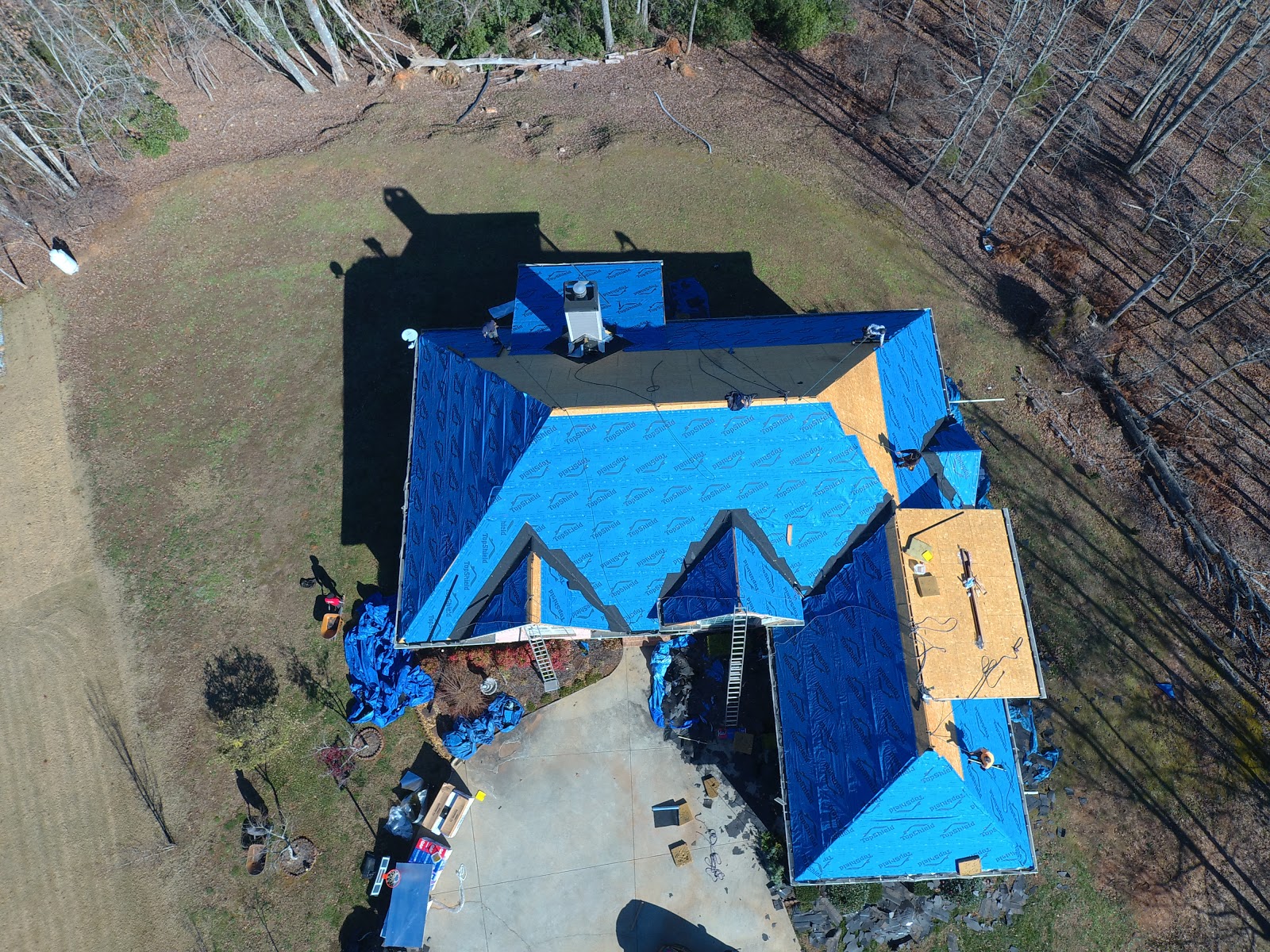 The Smart Company GA — aerial of storm-damage emergency roof tarping covering a multi-gable roof in blue poly