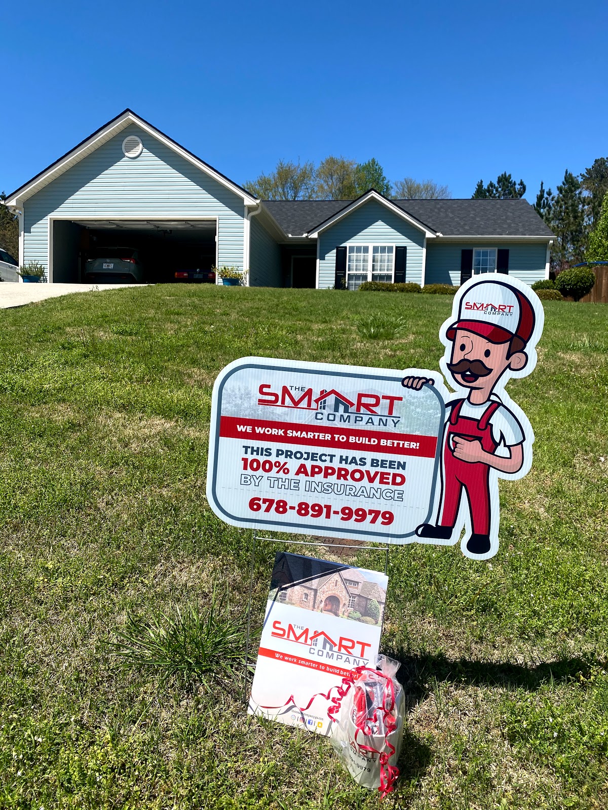 The Smart Company GA — branded yard sign displaying 678-891-9979 in front of a finished blue-siding home